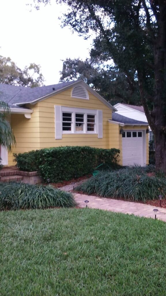 Older home restoration painting project with siding painted a rich yellow and beautiful pavers that were pressure washied by Miller's Pressure Washing.