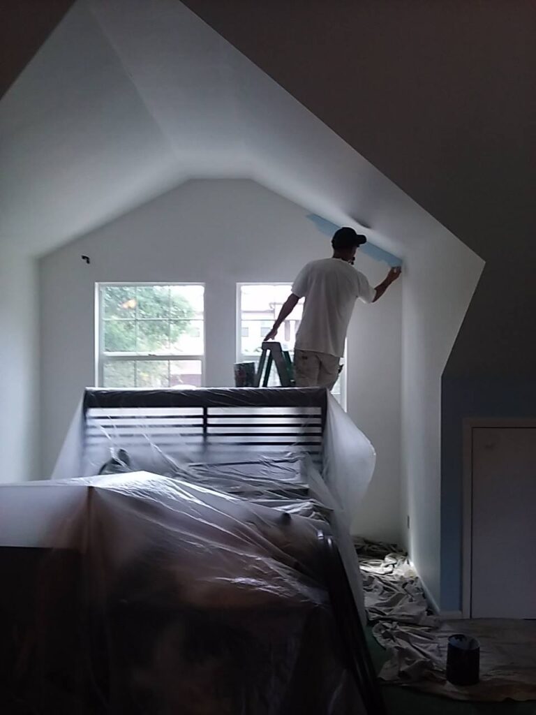 Miller's Pressure Washing painter cutting in a wall in a 2nd Story loft changing colors from white to a baby blue